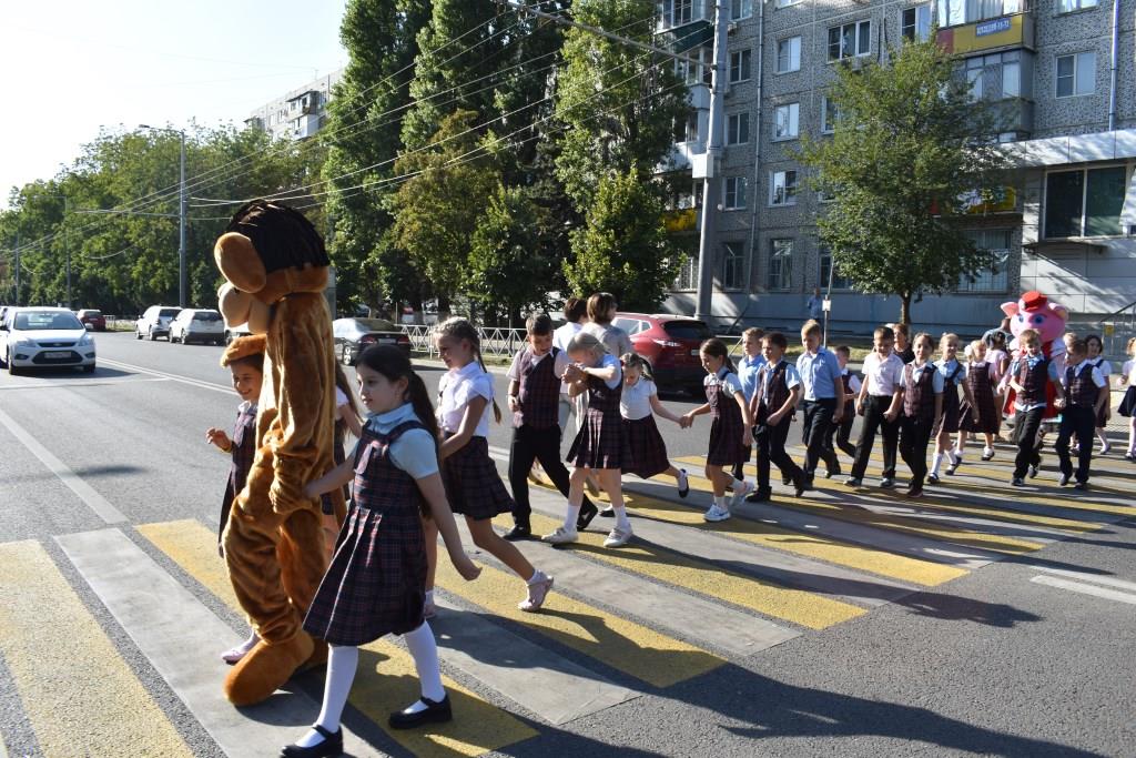 Дети переходят дорогу по зебре со светофором с пешеходной кнопкой.